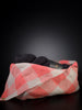 Coral pink and beige linen tie top bag open on a flat surface. It contains at least one skein of black yarn.