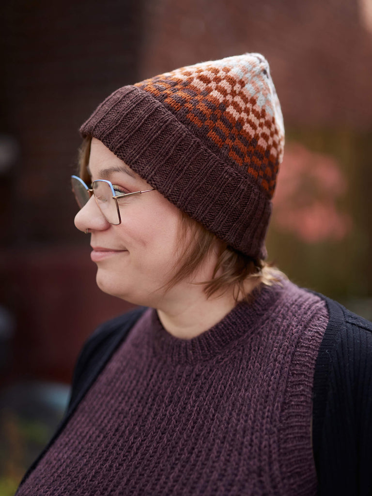 Person wearing a patterned knit hat and vest outdoors