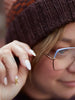 Person wearing a patterned knit beanie and glasses with a blurred background