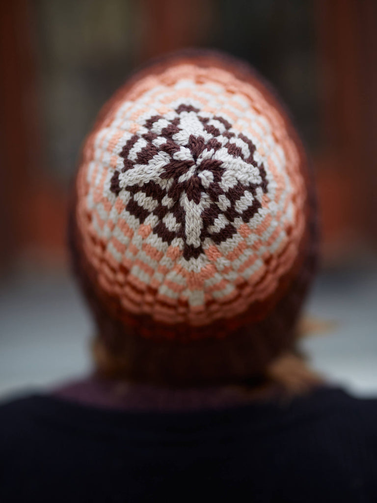 Person wearing a knitted hat with a pattern, blurred background
