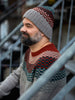 Man wearing a patterned knit hat and sweater sitting on metal stairs.