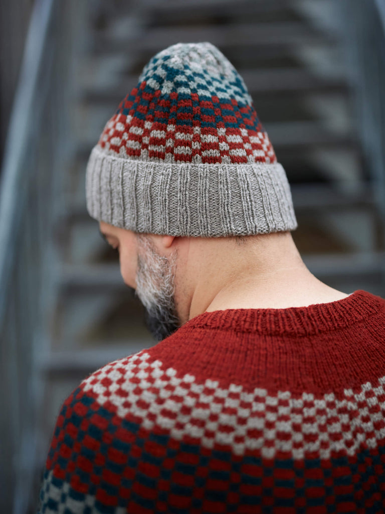 Person wearing a patterned knit hat and sweater against a blurred background