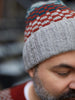 Person wearing a gray knit beanie with red and blue pattern, blurred background
