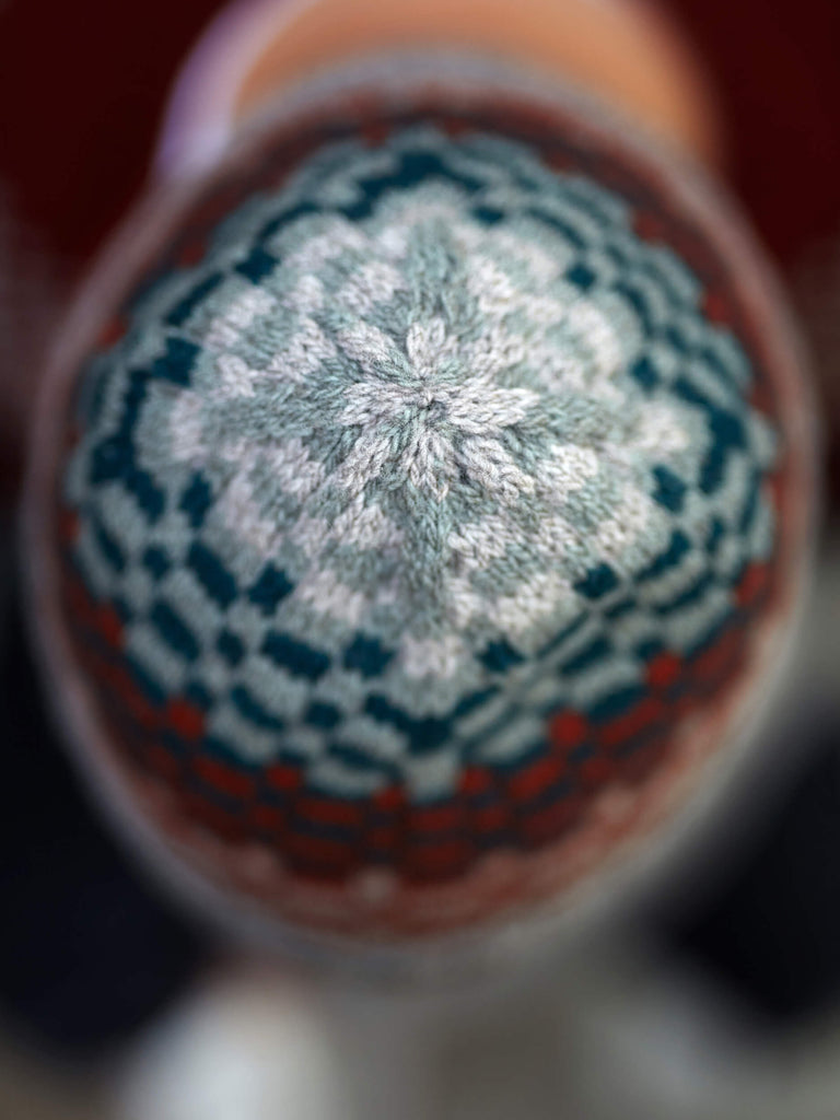 Close-up of a knitted hat with a geometric pattern on a blurred background